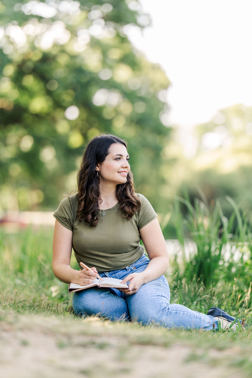 Young woman siting in the park with legs crossed towards the right.